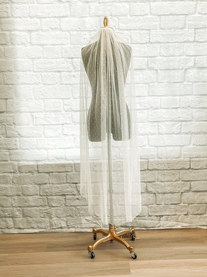 Lightweight dotted veil with comb, scalett has been displayed on a mannequin. This  veil is being shown in a waltz length. 