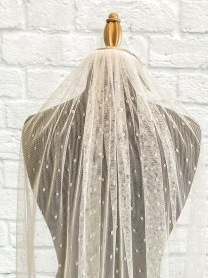 A close up of the gathered comb and top pf the swiss dot veil, scarlett. displayed on a dark mannequin you an easily see the  ¼" dots on tulle veil. 