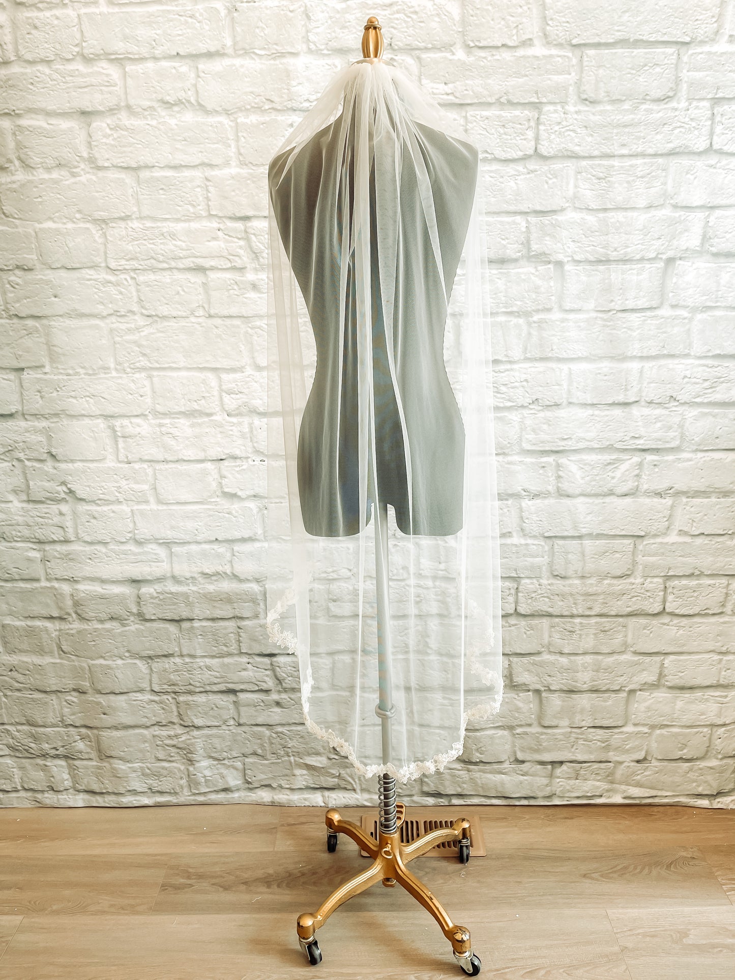 The full length view of the Haven wedding veil with beaded and sequined lace trim at the curved hem of the veil. Displayed on a mannequin in a pale ivory Waltz calf length. 