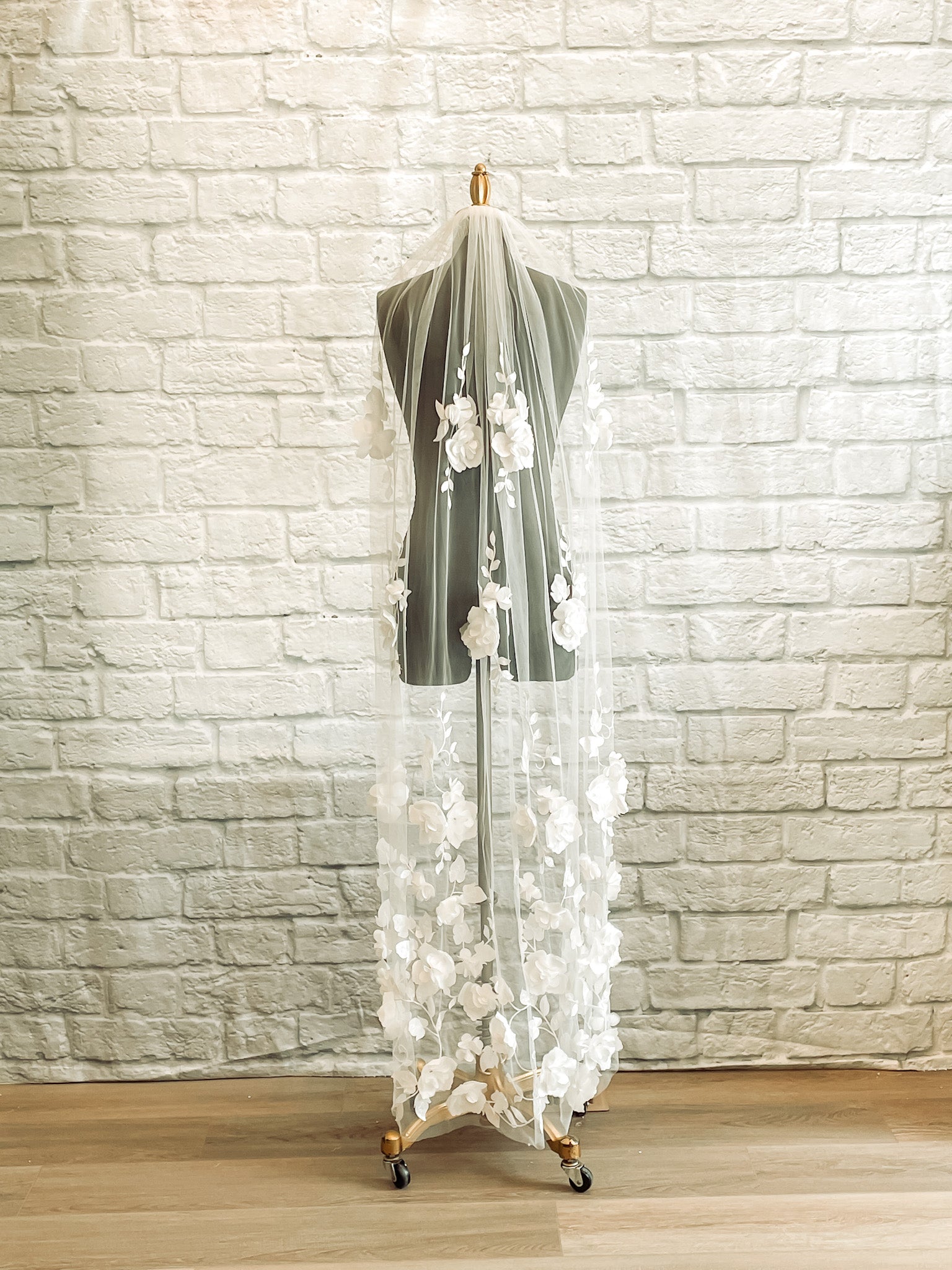 A full length photo of the Celine veil in pale ivory waltz length displayed on a mannequin. The veil has a Lightweight tulle base with 3D flower lace details.