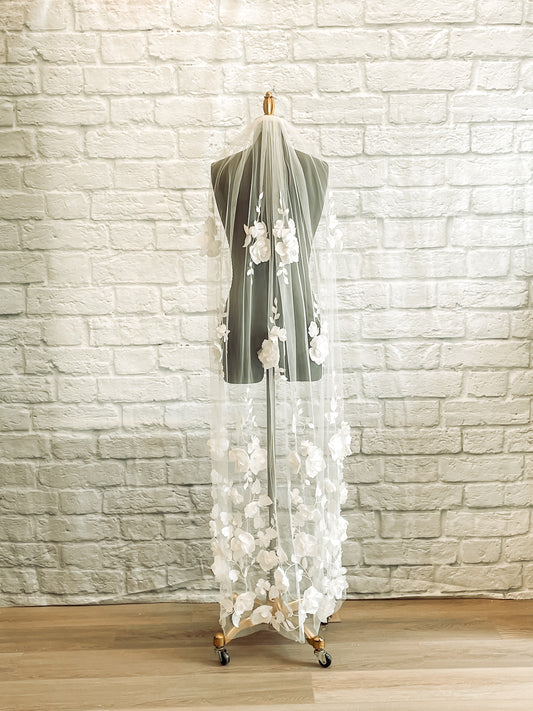 A full length photo of the Celine veil in pale ivory waltz length displayed on a mannequin. The veil has a Lightweight tulle base with 3D flower lace details.