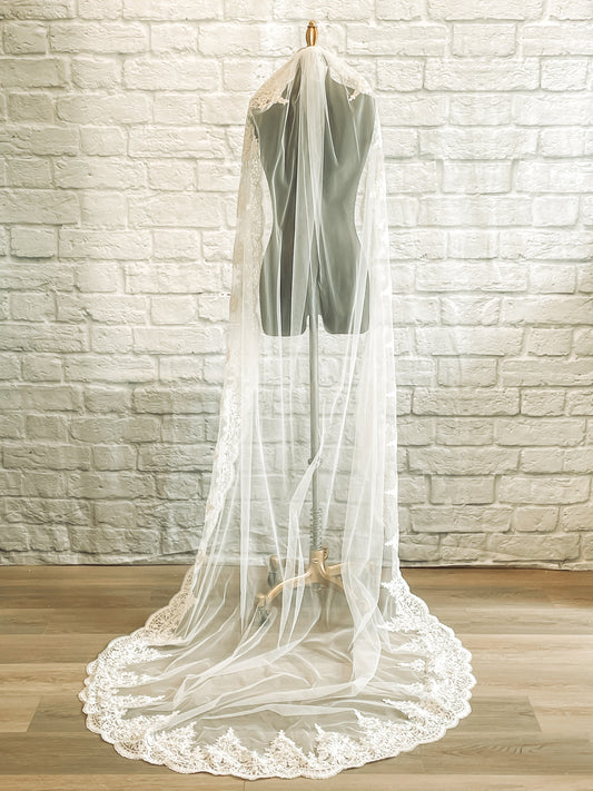 Back view of the April veil in chapel length, showcasing the full lace edging cascading over a mannequins shoulders for a timeless, romantic effect.