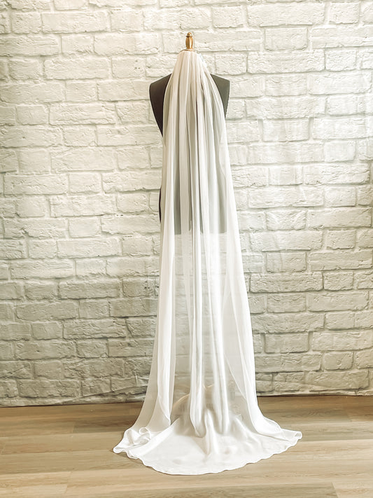 A floor length chiffon veil shown on a mannequin in white. 