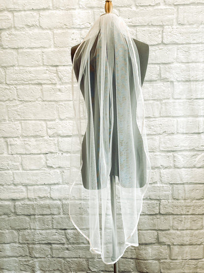 A closer image of the bridget veil hung up on a mannequin in white calf length. 