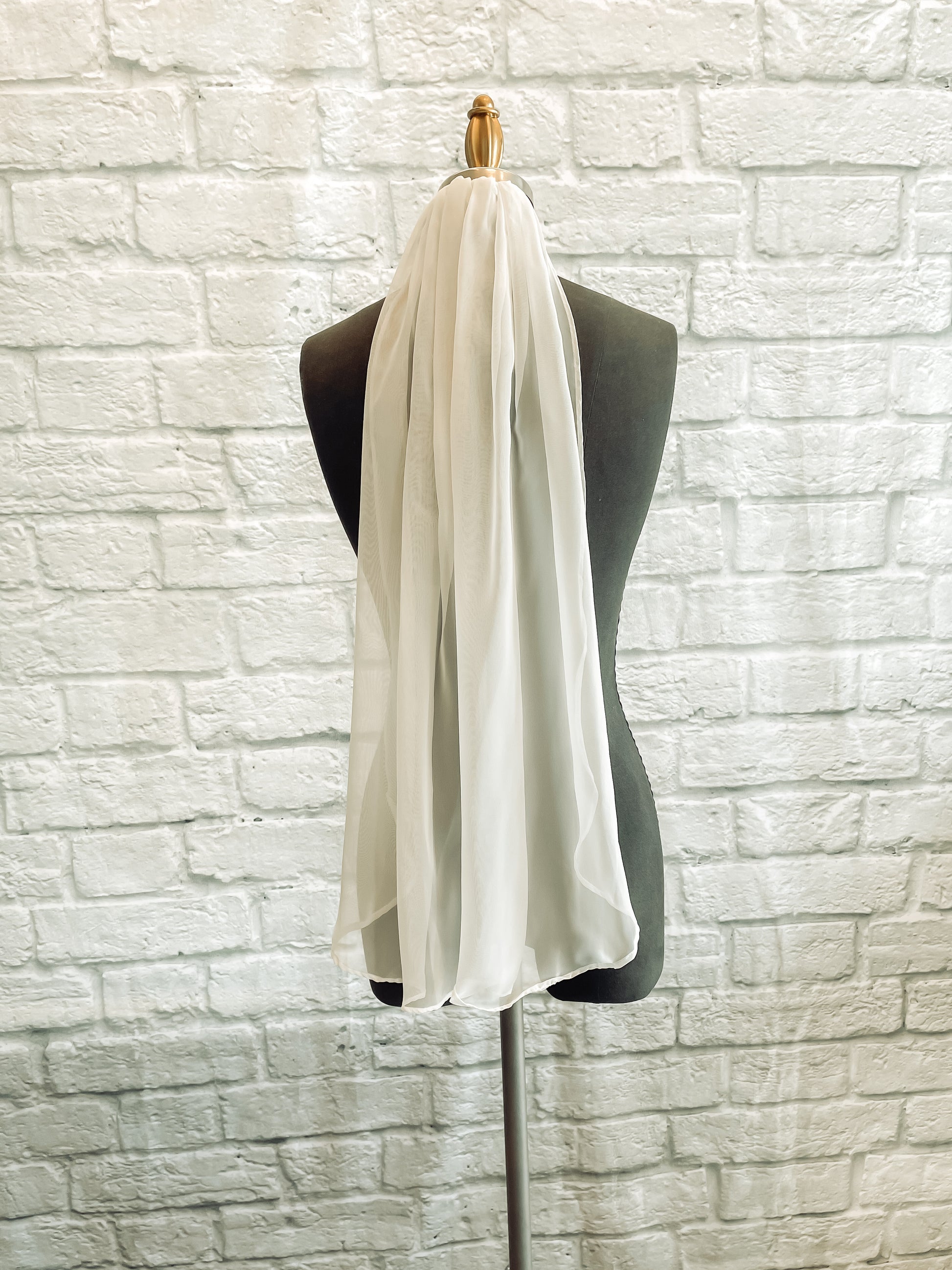 A fingertip length Braelyn veil in ivory; this chiffon veil is displayed on a mannequin.