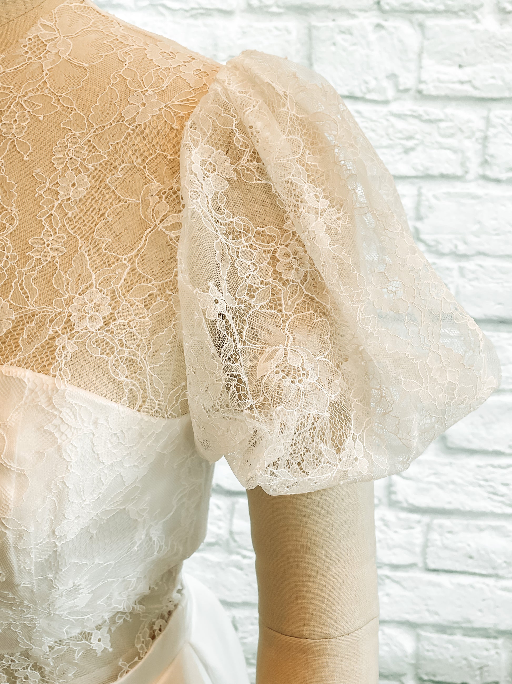 Sleeve close up, gathered lace sleeve at shoulder and hem with delicate pattern. 