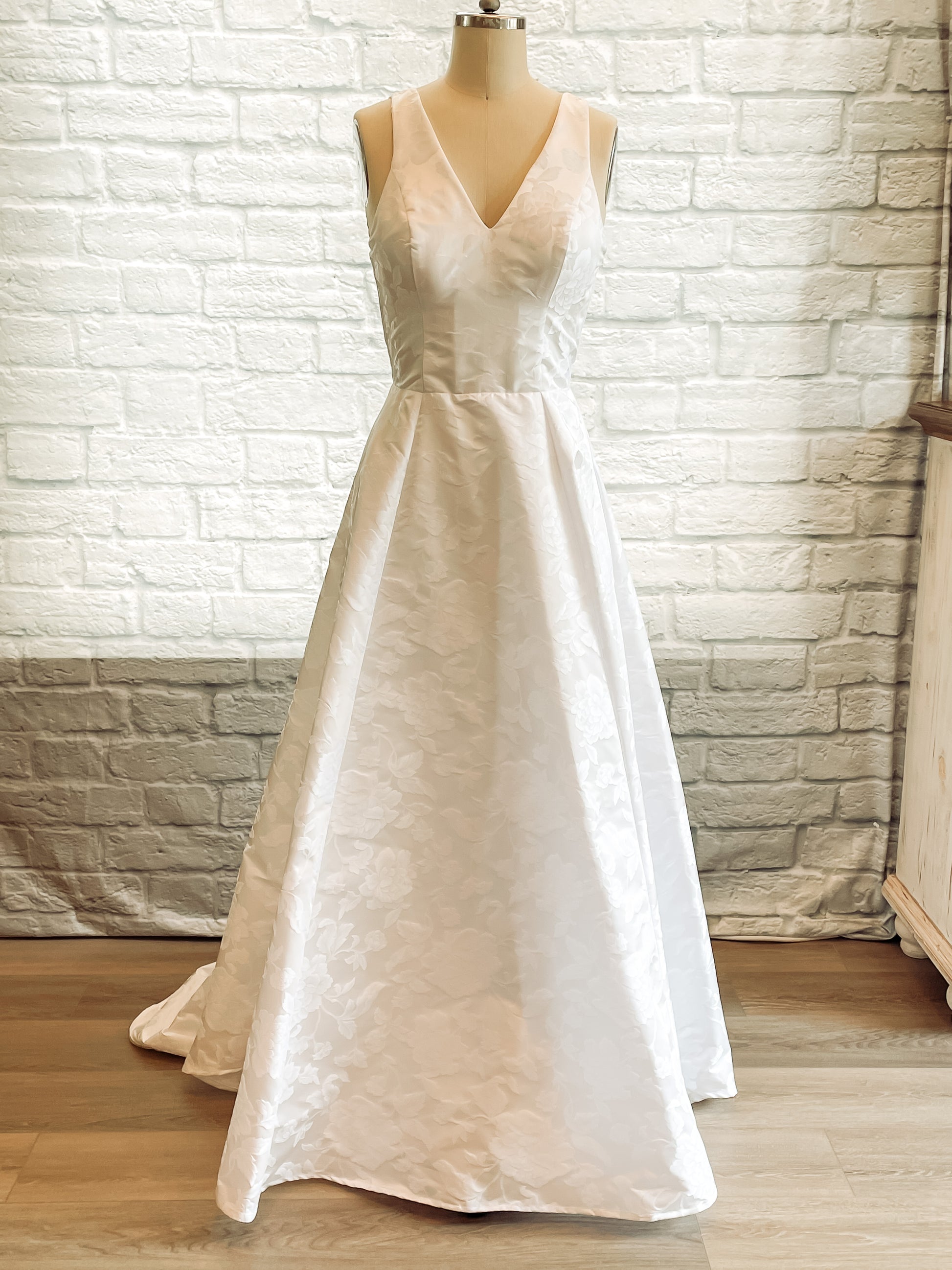 Madison gown on a manniquin showing the A-line wedding gown in floral jacquard with V-neckline. 