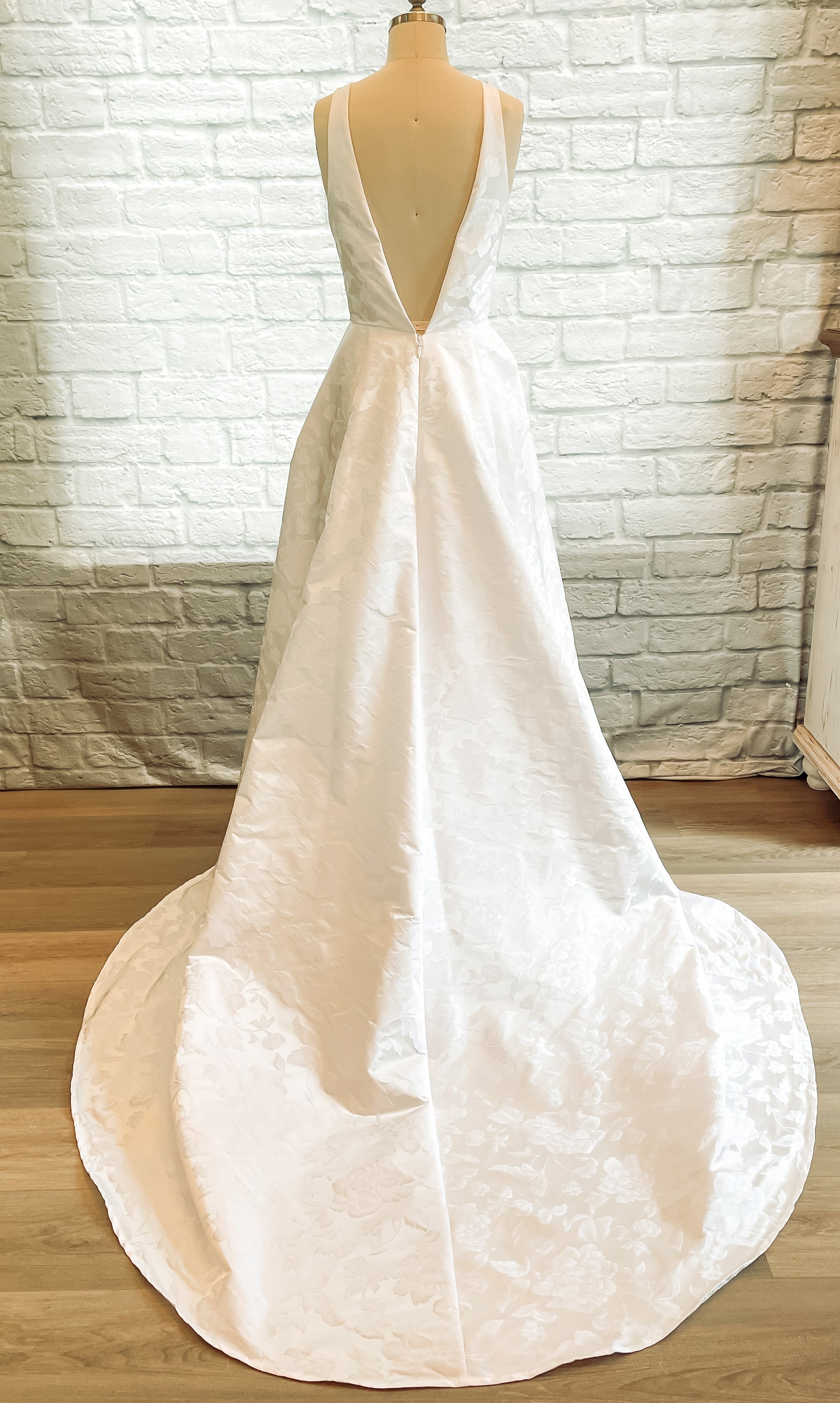 Back view of the Madison gown showing the V-back jacquard wedding dress in white with a flowing train.