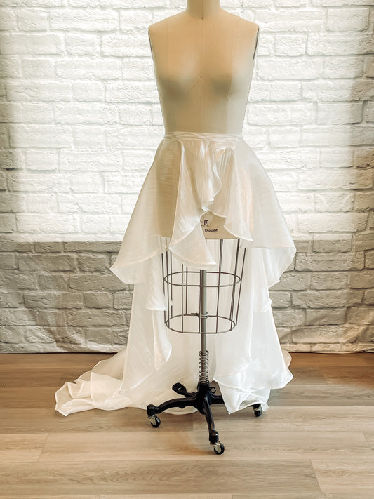 Full-length view of a mannequin wearing the Amber removable organza skirt, showing cascading ruffles and a soft train