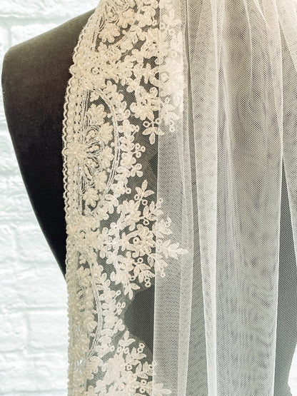 A close up of the edge of the Ireland veil with fan-shaped beading and mini scalloped edges sewn to a tulle base. 