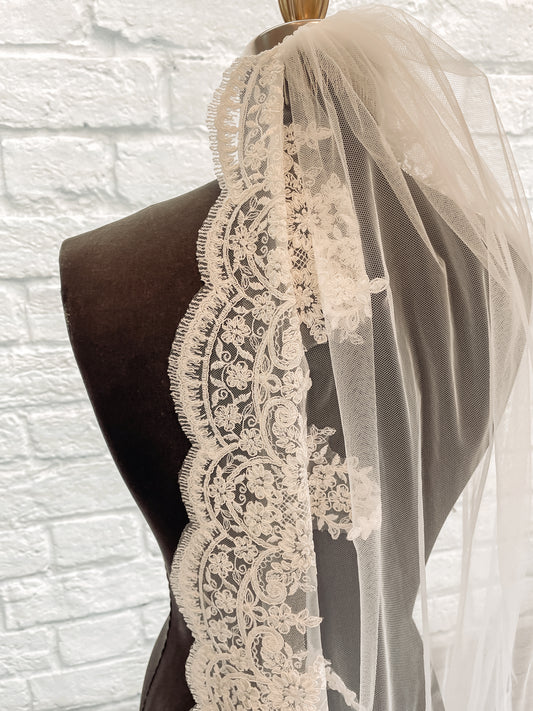 Close-up of the embroidered lace trim on the April veil, highlighting the intricate floral pattern against the pale ivory tulle.