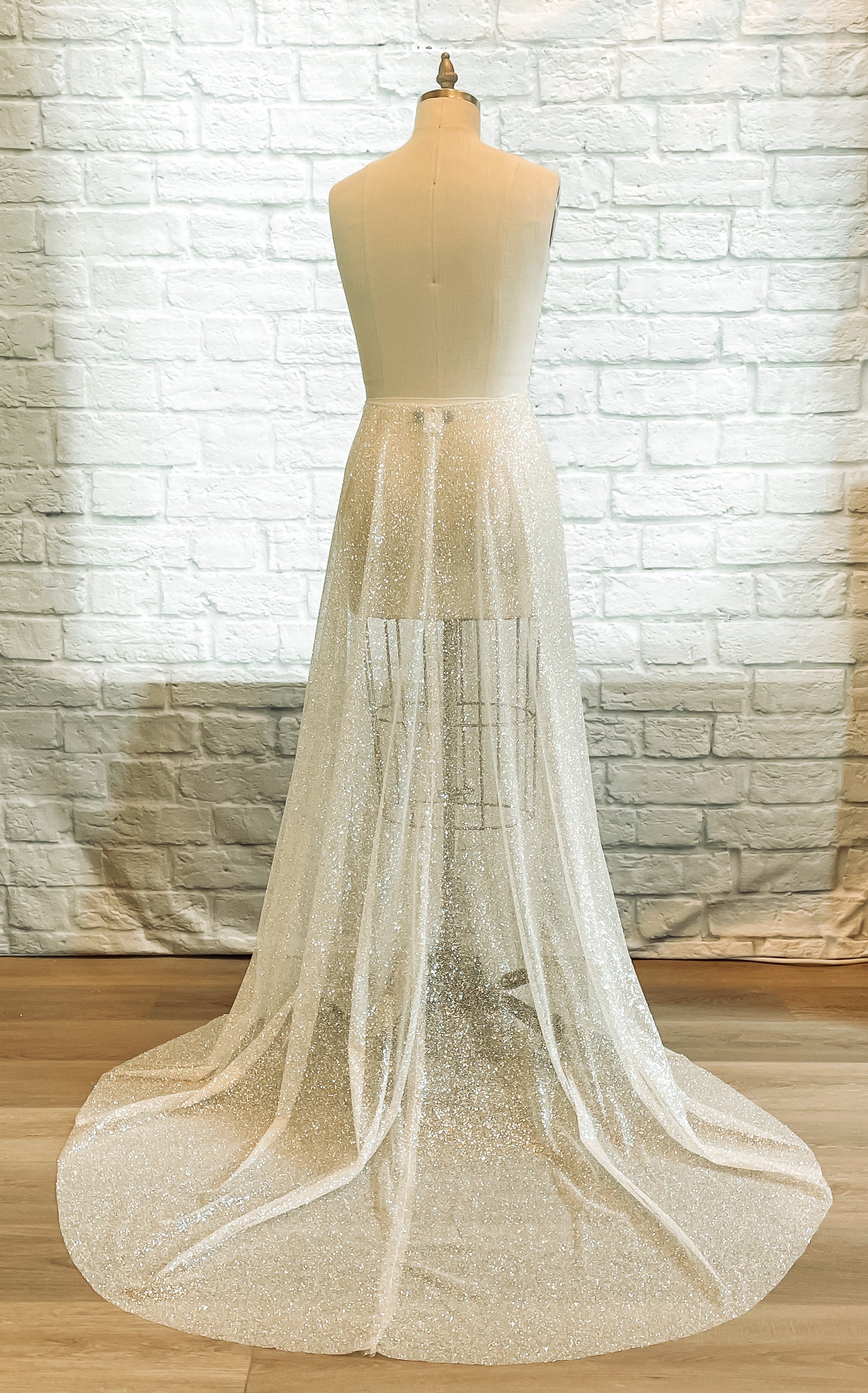 A full length back shot of the glitter tulle skirt, calliope, with a 27" long train displayed on a mannequin. 
