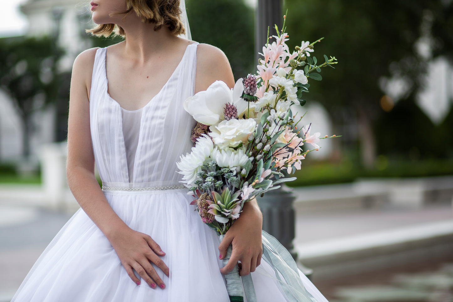 A close up of the front bodice of persephone showing off the deep plunge, gathered tulle bodice, tank style straps and gathered skirt. The Fleur belt can be seen paired with this gown. 