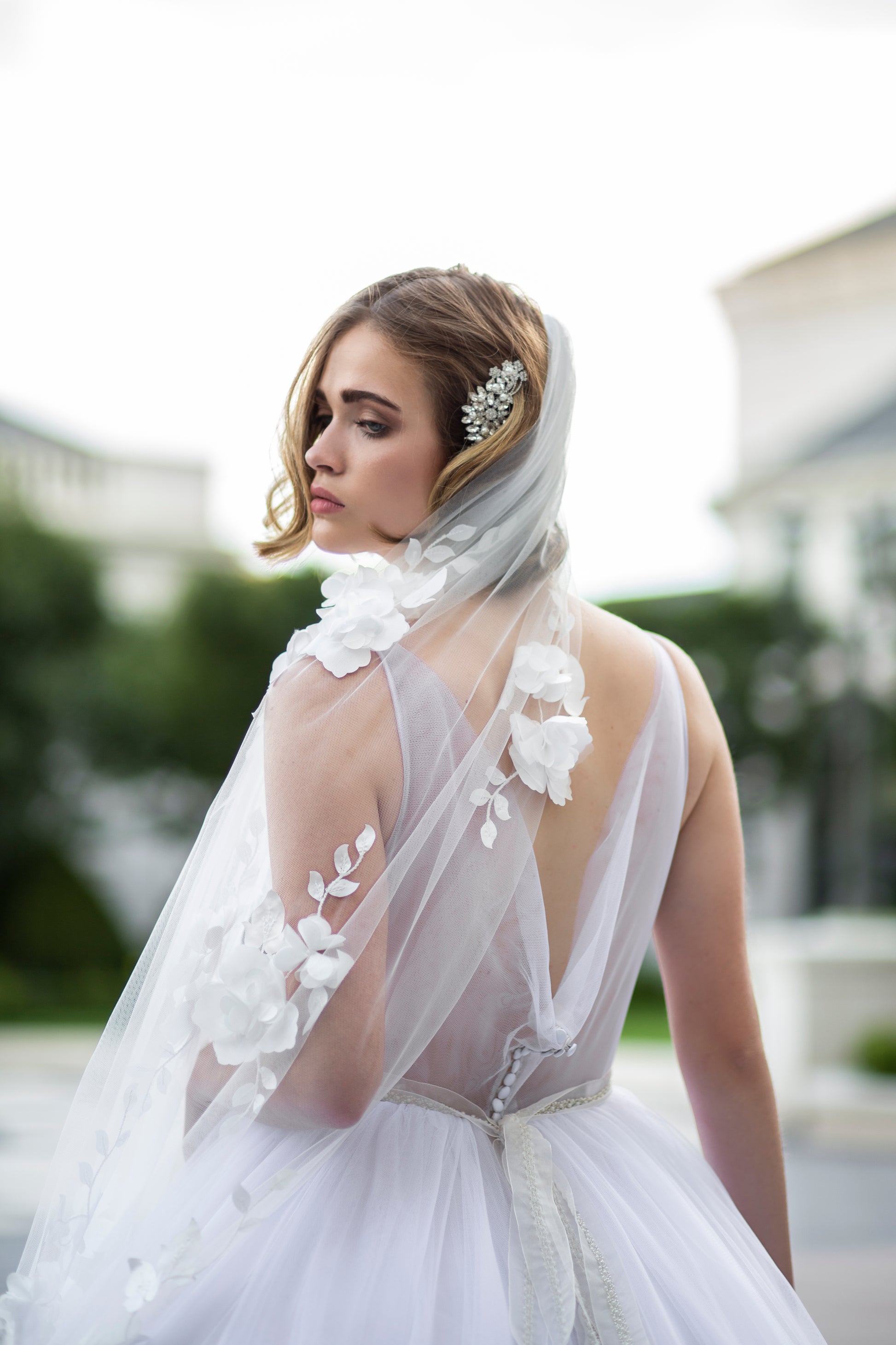 A styled shoot of the Persephone gown with 3D floral Celine veil for a romantic finish. The back bodice is visable with the button closure, cowl back neck and gathered tulle skirt. 