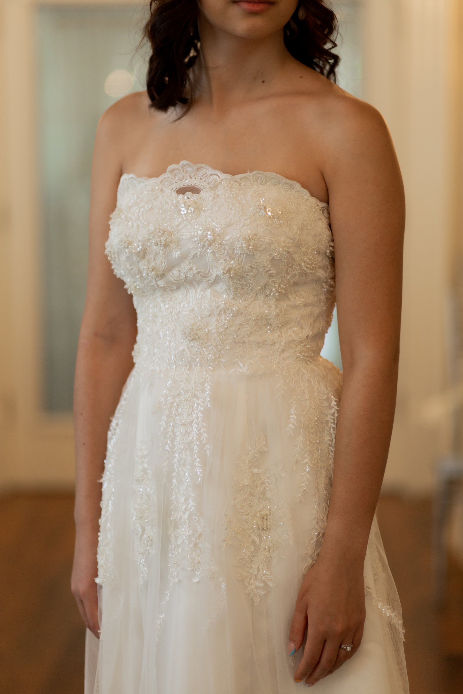 A close up bodice and top skirt view of the kennsington gown, this beaded bodice has 3d bead clutsters and cascading lace into the skirt. 
