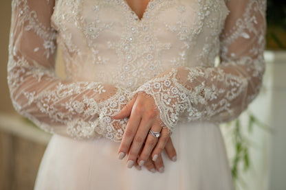 Detail shot of sleeve hem, focusing on eyelash lace scalloping at the knuckles; the lace bodice is slightly out of focus behind.