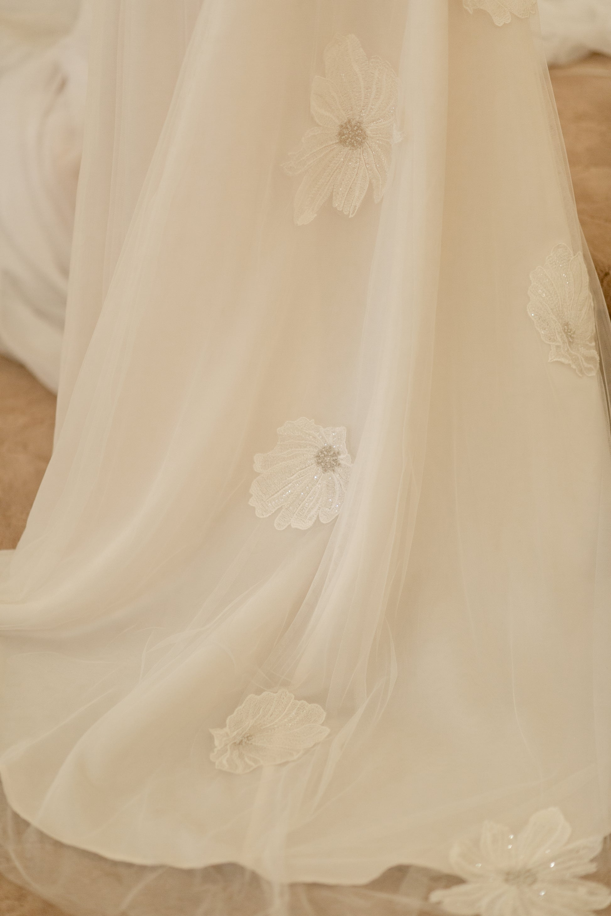 The train of the poppy gown stretches back toward the camera; the Three-layer soft tulle train has floral lace down center back.
