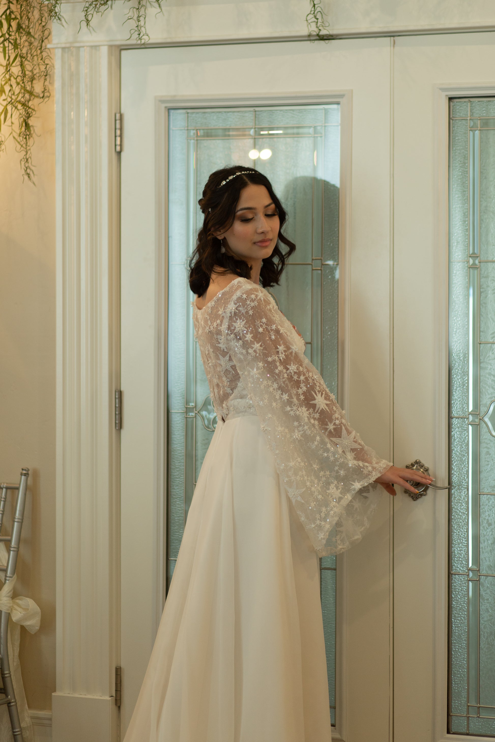 Bride wearing Novelli wedding gown with star beaded lace and chiffon overlay posing indoors