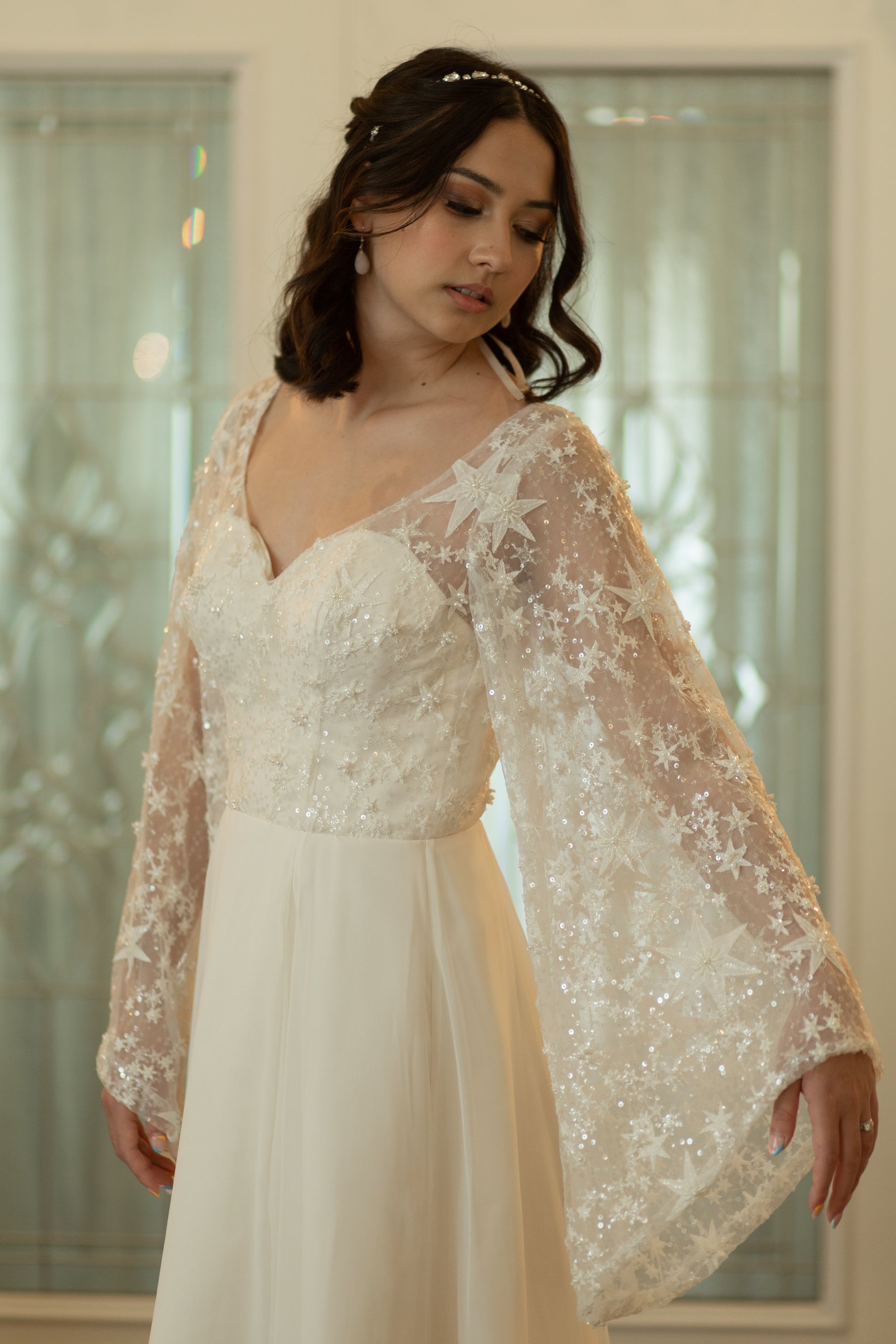 Novelli bridal gown with celestial lace and dramatic bell sleeves shown in romantic setting