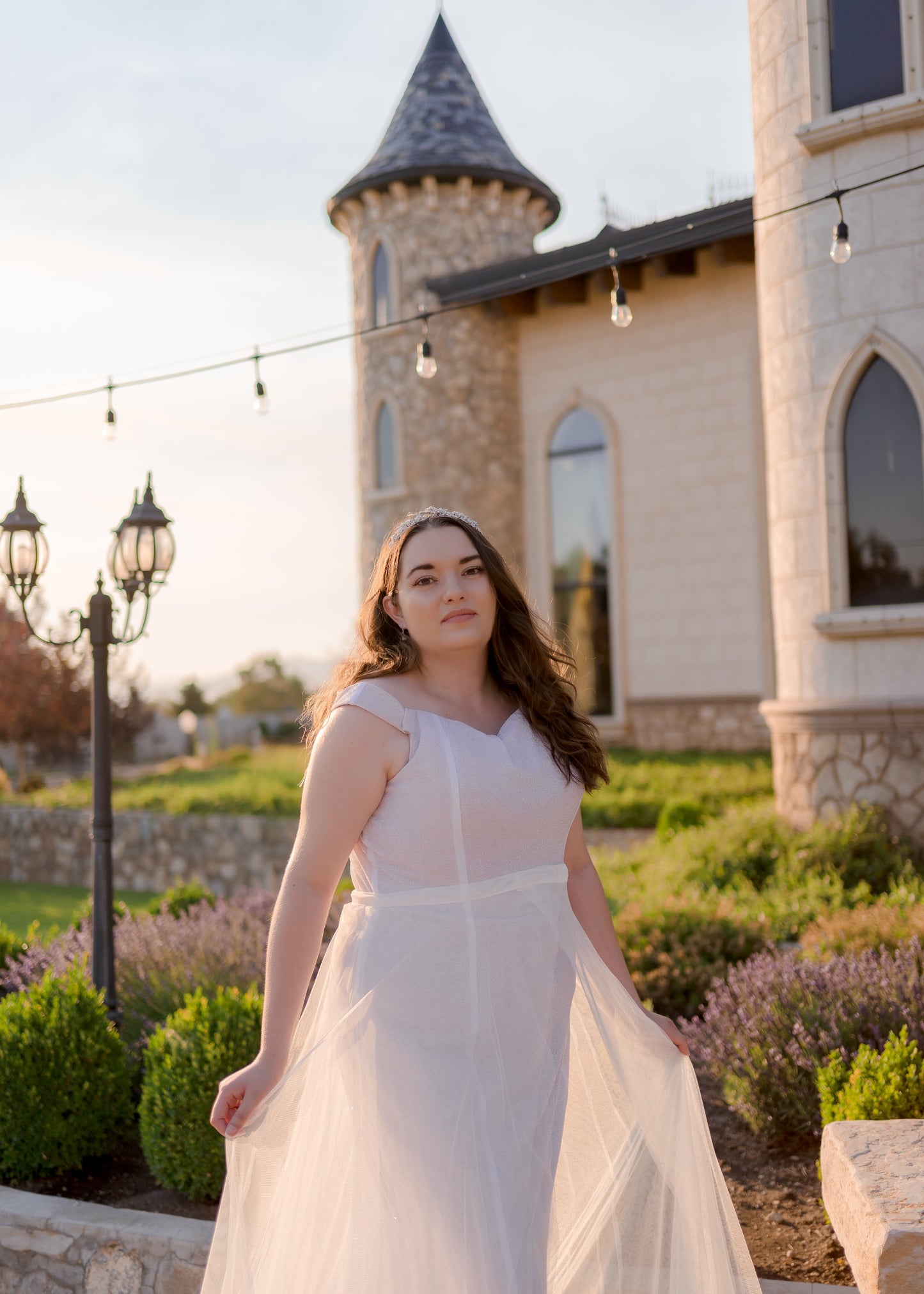 A close up Side angle of the removable bridal skirt highlighting layered tulle over a fit and flare gown, alora. 