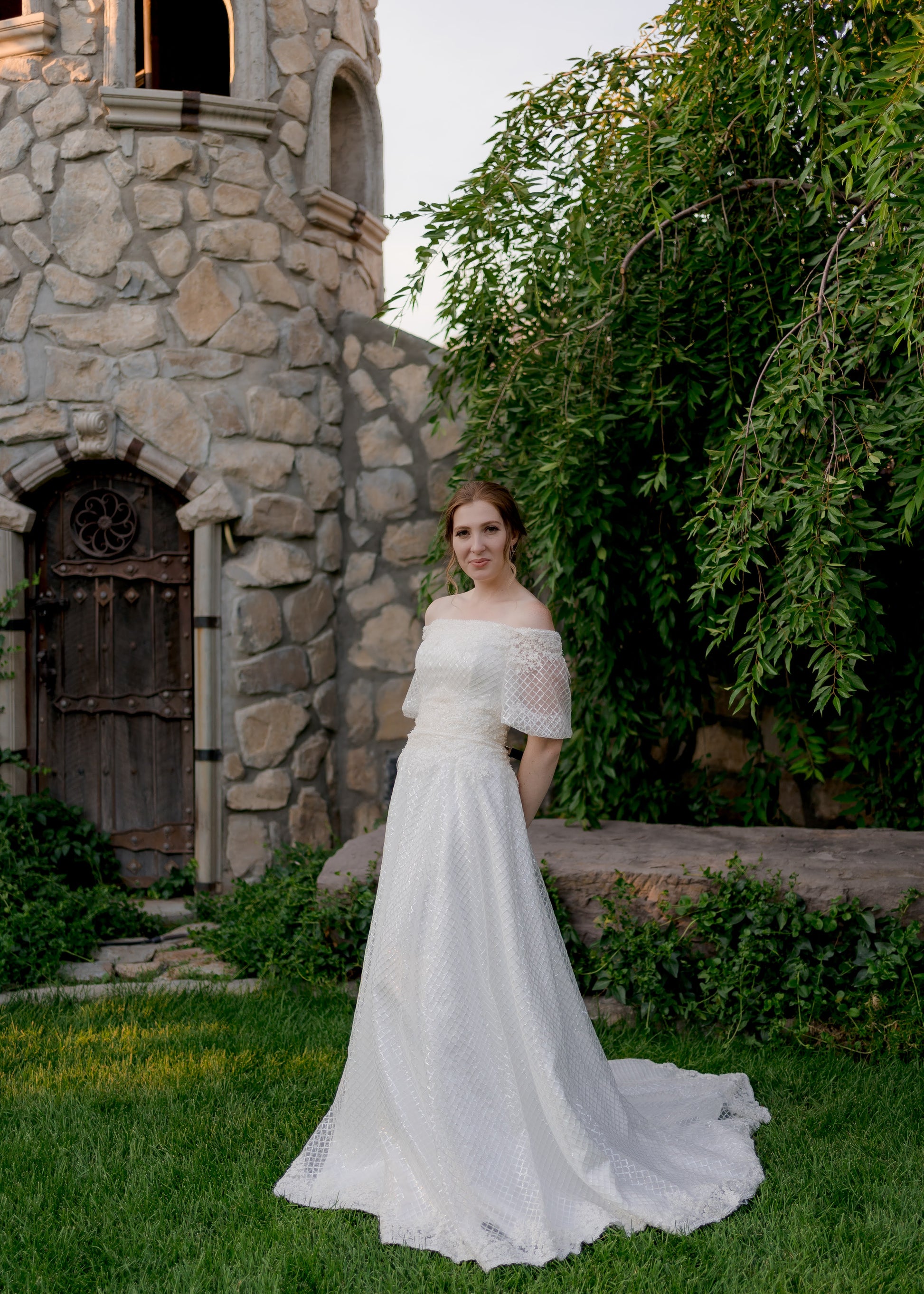 Styled shot of a bride wearing the parker gown, she stands on a ¾ angle and you can see the structured bodice, a-line shape and puff sleeves.