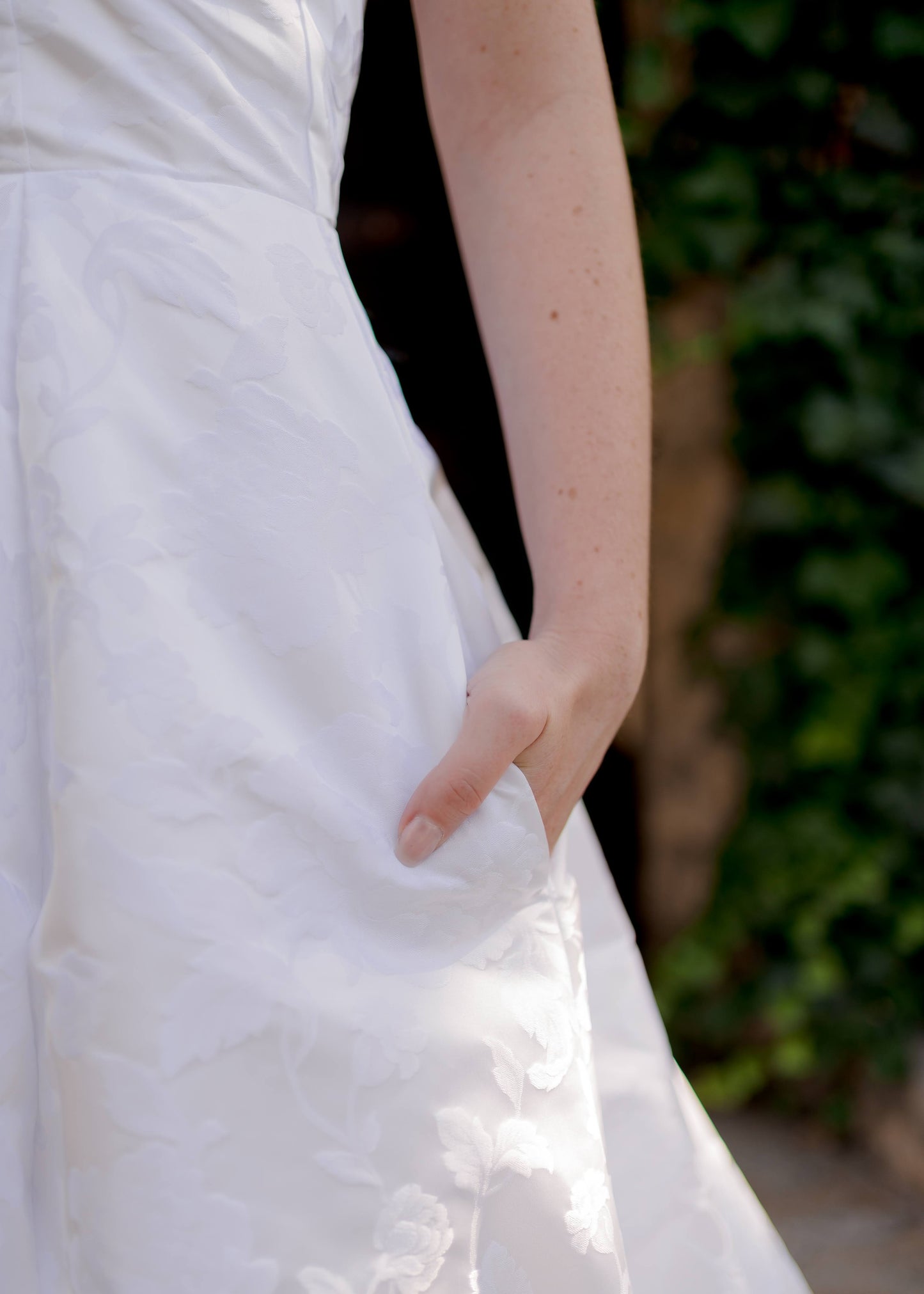 Bride’s hand in side seam pocket of jacquard wedding gown, Madison.