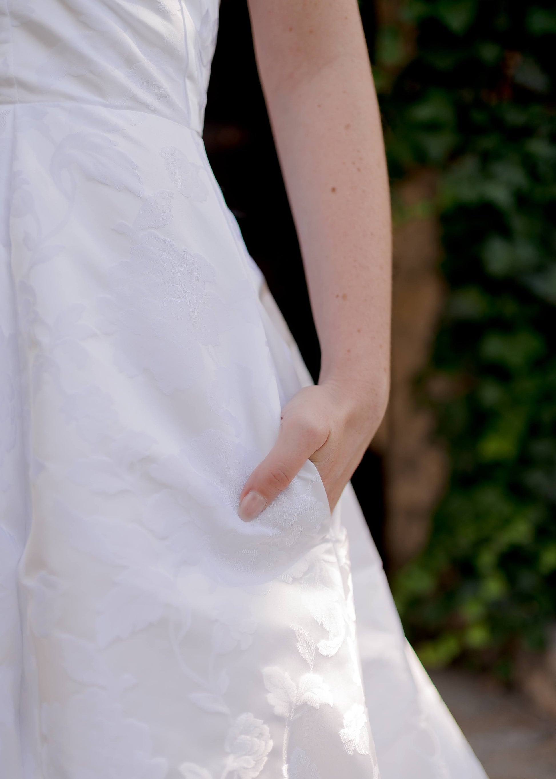 Bride’s hand in side seam pocket of jacquard wedding gown, Madison.