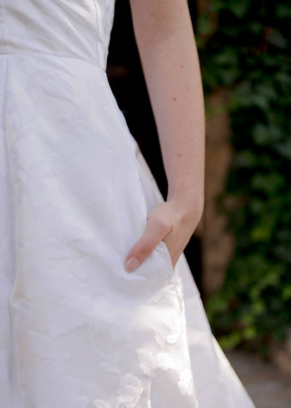 Bride’s hand in side seam pocket of jacquard wedding gown, Madison.