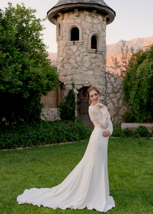 The Zuri wedding gown on a model in a full side view image; the mermaid fit through hips with soft flare at knees leads into the elongated train. 