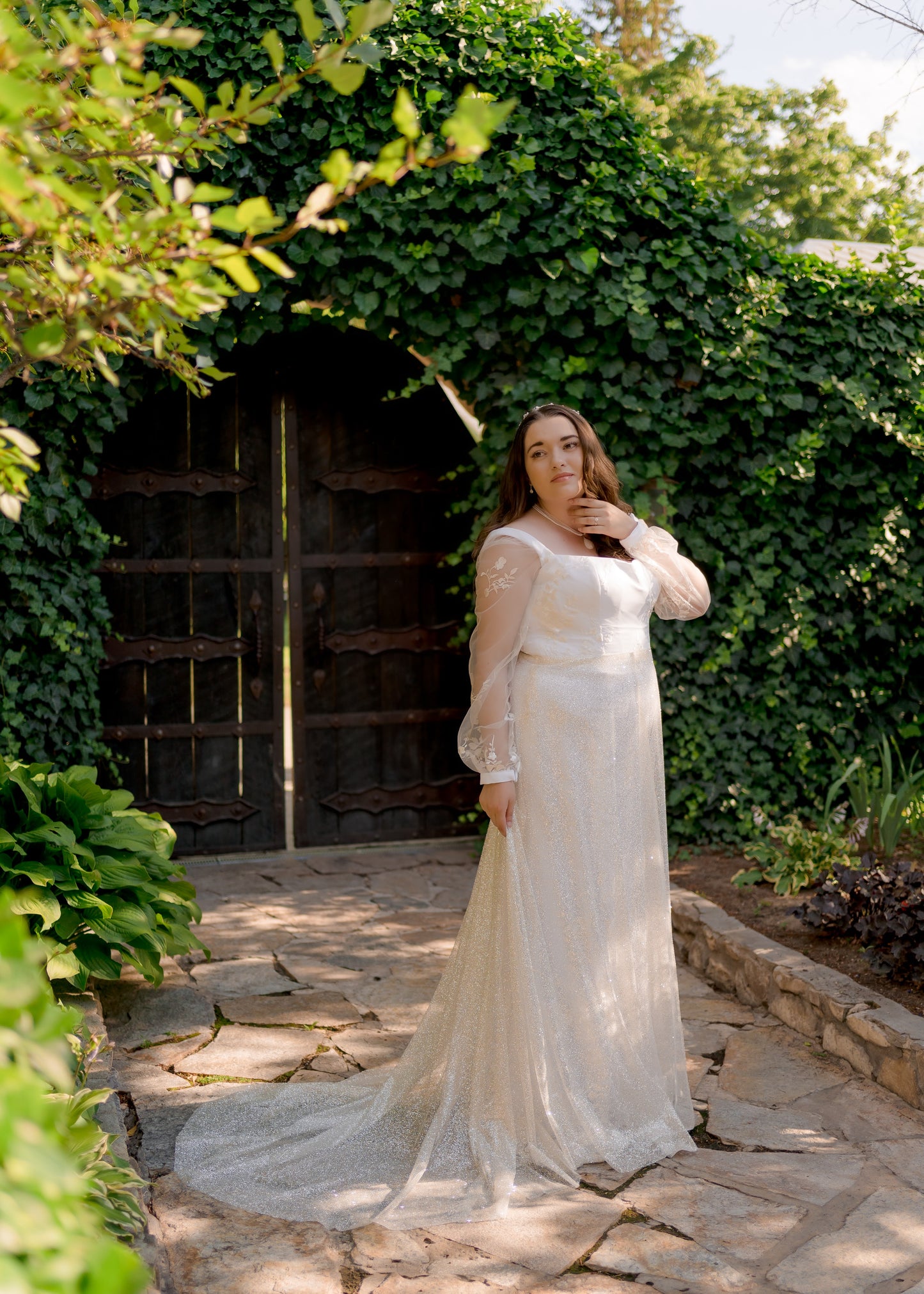 A side view of a bride wearing the violet gown styled with the removable glitter skirt, Calliope, showing off the 20-inch train stretched out to the side.