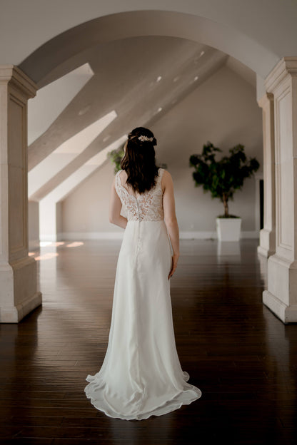 A full length back shot of the Winifred gown in Ivory on a bride with the flowy chiffon and satin train and the lace textured bodice. 
