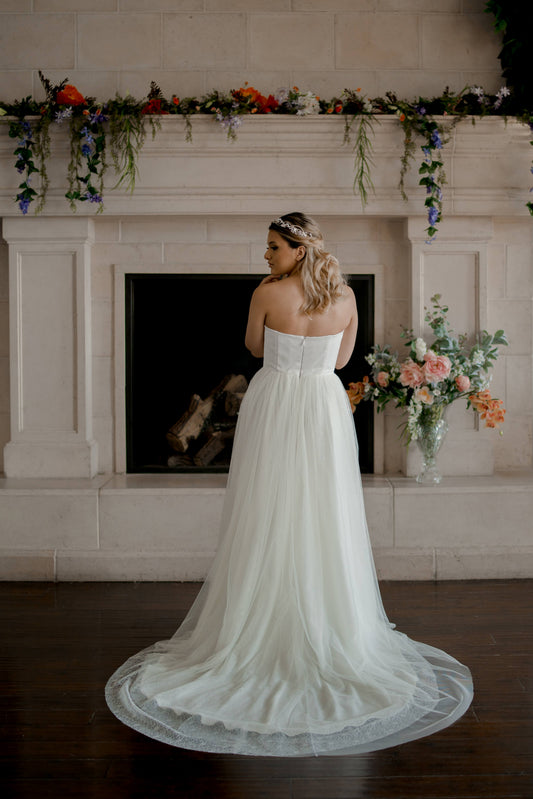 Back view of the Beatrice wedding dress on a model, highlighting the layered tulle and lace train that extends gracefully behind.