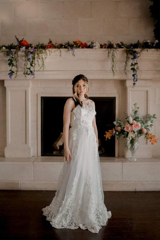 A bride wears the Jacqueline wedding gown with illusion straps, sweetheart neckline, and butterfly lace overlay. 