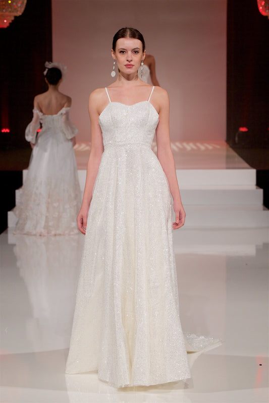 Movement shot of the full front of the gown and train sweeping behind the model, walking down a runway.
